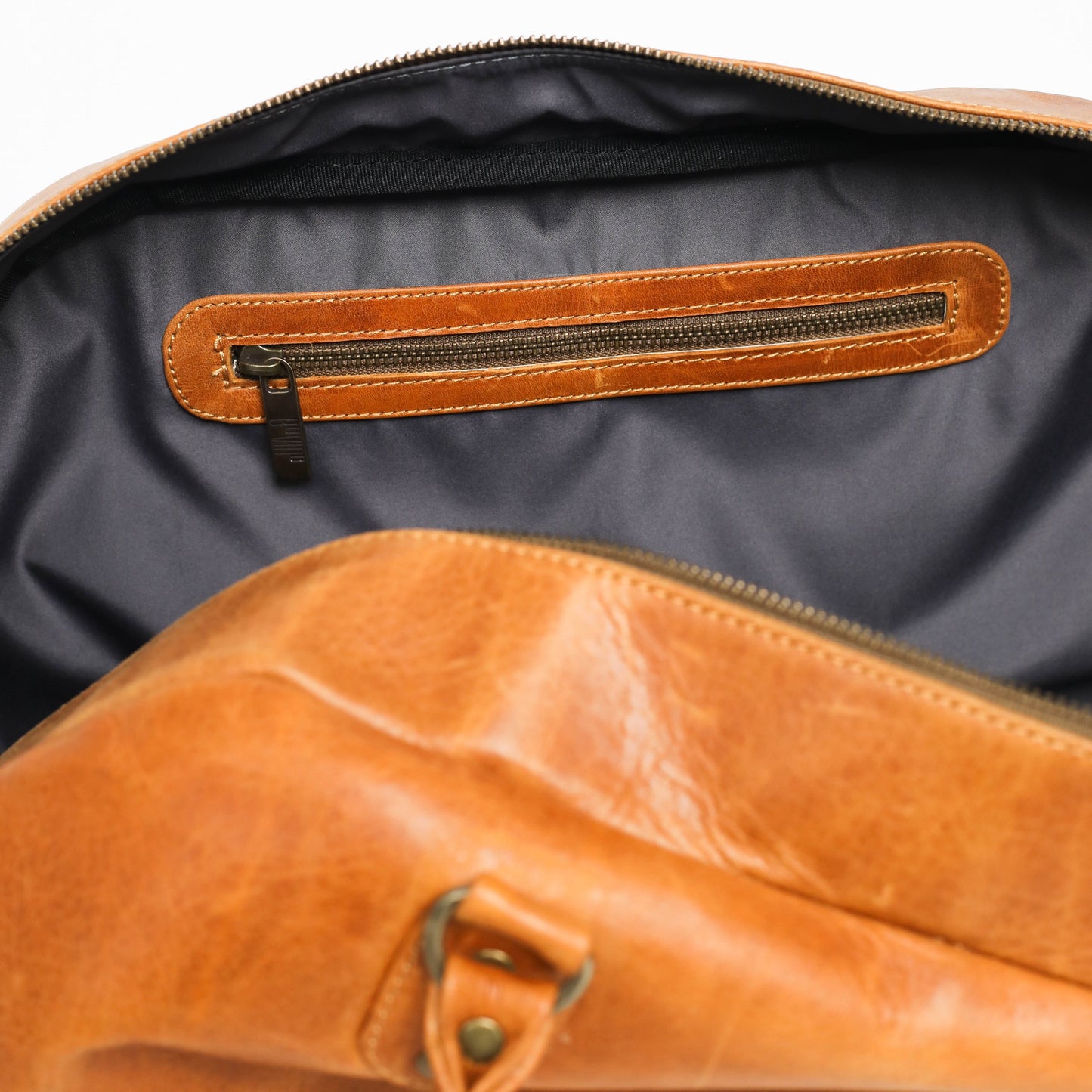 Brown leather bag with open zipper on a white background