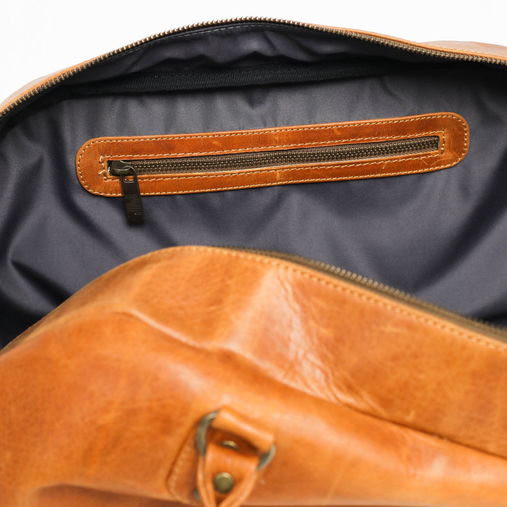 Brown leather bag with open zipper on a white background